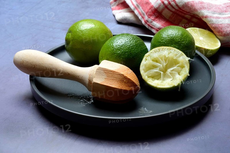 Limes with citrus squeezer on plate