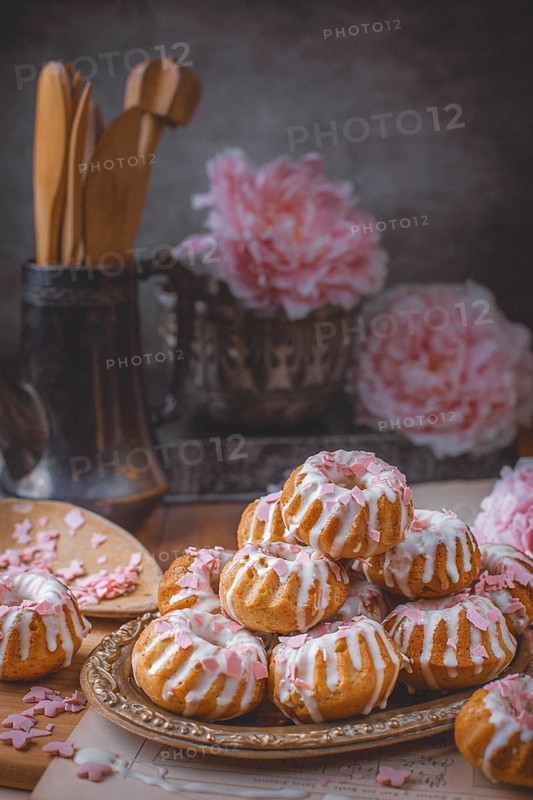 Muffins with pink icing in front of peonies (Paeonia)