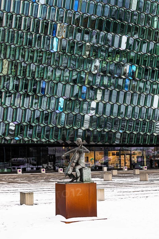 Bronze sculpture of the man with the cello, behind it the glass facade of the Harpa concert hall and congress centre, Reykjavik, Reykjanes Peninsula, Sudurnes, Iceland, Europe