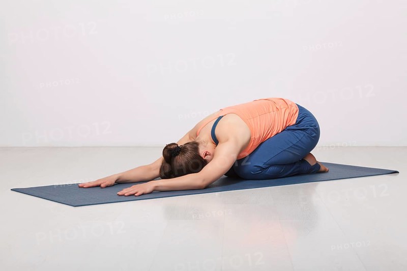 Beautiful sporty fit yogini woman practices yoga asana balasana (child's pose), resting pose or counter asana for many asanas in studio