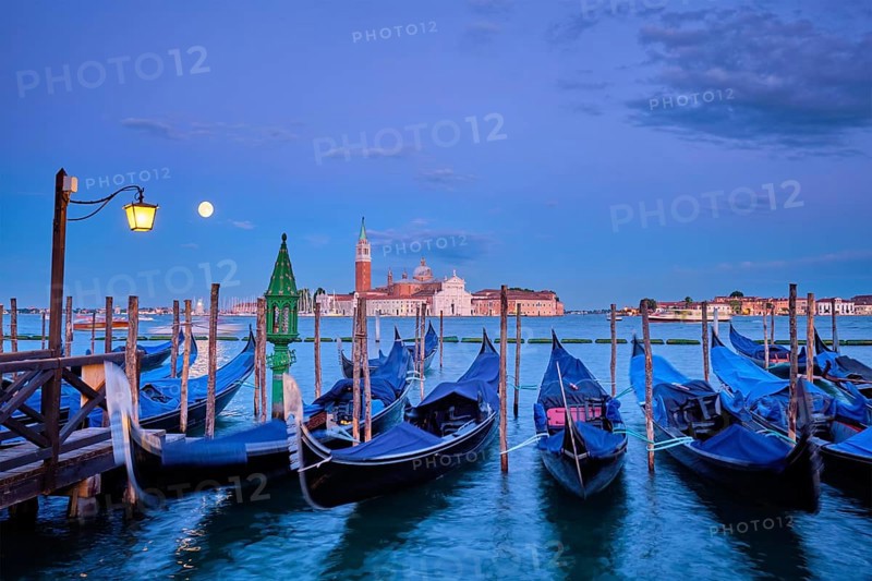 Romantic vacation Venice travel background, gondolas at Saint Mark (San Marco) square and Basilica San Giorgio Maggiore Church seen across Venice lagoon with full moon. Venice, Italy, Europe