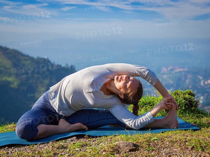 Yoga outdoors, young sporty fit woman doing Hatha Yoga asana parivritta janu sirsasana, Revolved Head-to-Knee Pose, in mountains in the morning