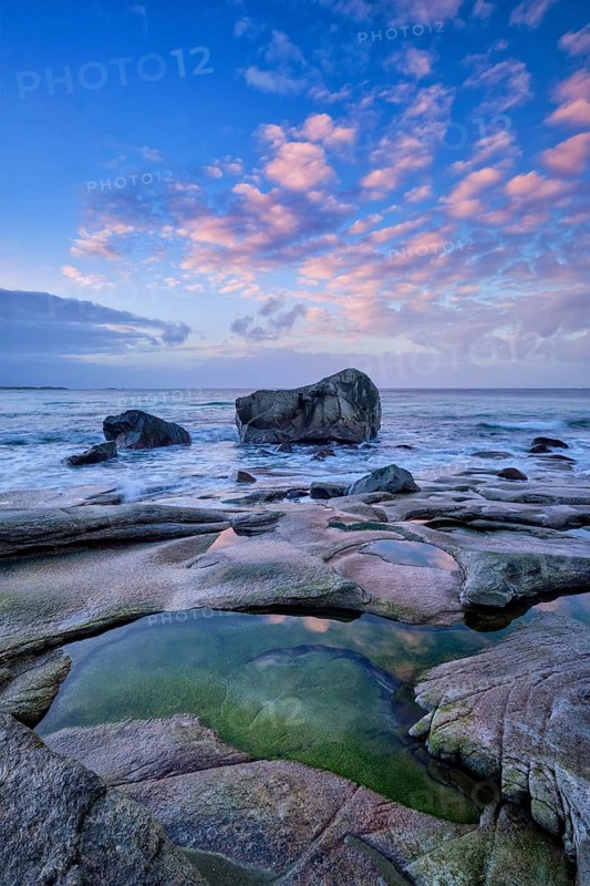 Rocks on beach of fjord of Norwegian sea in winteron sunset. Utakliev beach, Lofoten islands, Norway, Europe
