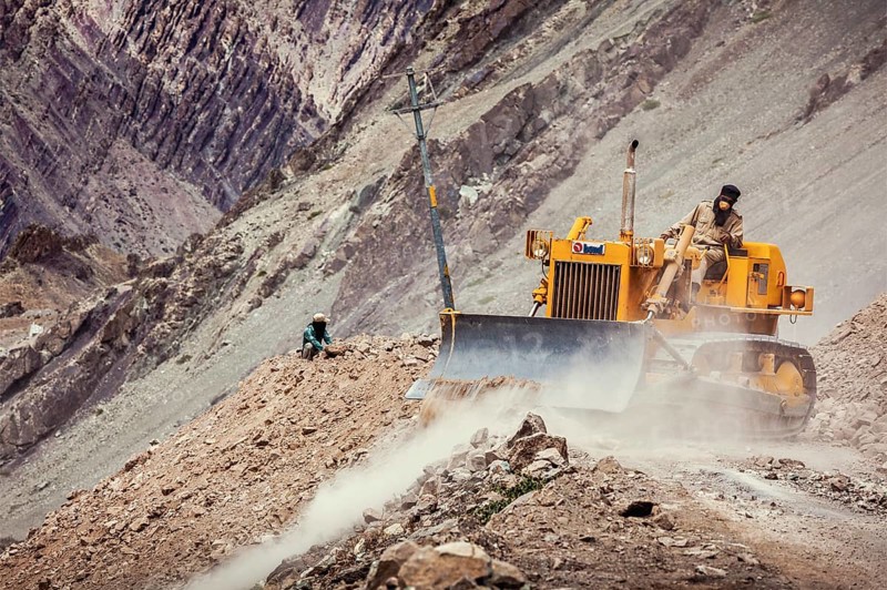 LADAKH, INDIA, SEPTEMBER 10, 2011: Bulldozer cleaning road after landslide in Himalayas. Ladakh, Jammu and Kashmir, India, Asia