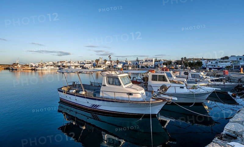 Fishing boats in the harbour of Naoussa at sunset, reflected in the sea, White Cycladic houses, Naoussa, Paros, Cyclades, Greece, Europe