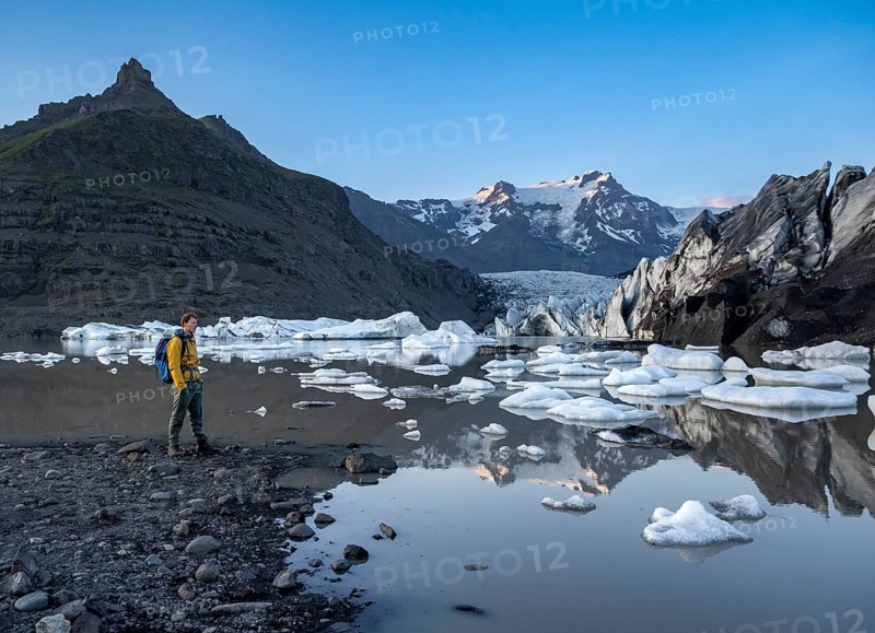 Hikers at a lake, reflection in the Svínafellslon glacier lagoon with ice floes, Svínasfellsjökull glacier tongue, glaciated mountain peak Hrútfjallstindar in the background, at sunset, Svínafell, Iceland, Europe