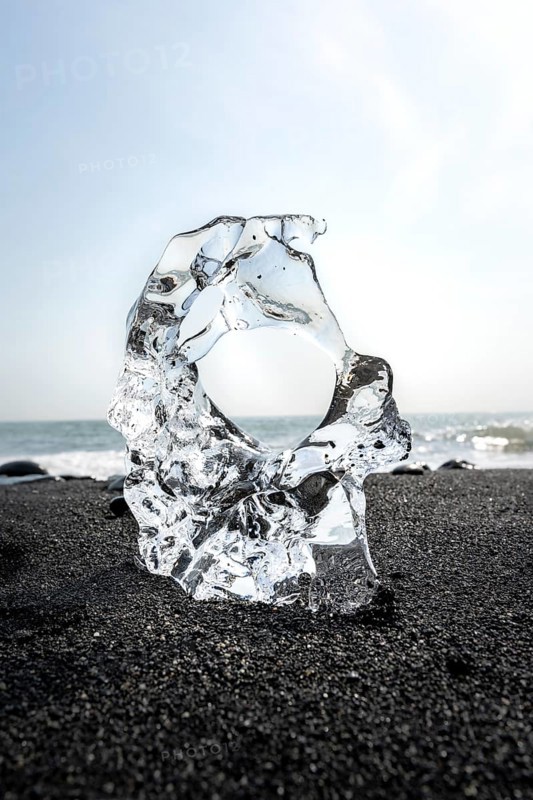 Ice, piece of ice with hole on black sand beach, on black lava beach Diamond Beach, Southeast Iceland, Iceland, Europe