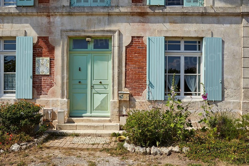 Picturesque old house with flowers, shutters, windows, door and sundial on the island of Île-d'Aix, Charente-Maritime, France, Europe