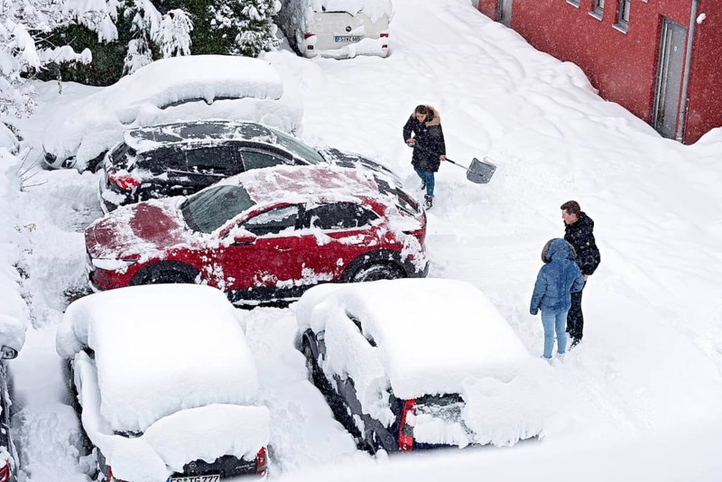 Woman shovelling snow on car park, car, car, snowed in, fresh snow, heavy snowfall, snow masses, snow chaos, snow shovel, onset of winter, Marzling, Freising, Upper Bavaria, Bavaria, Germany, Europe