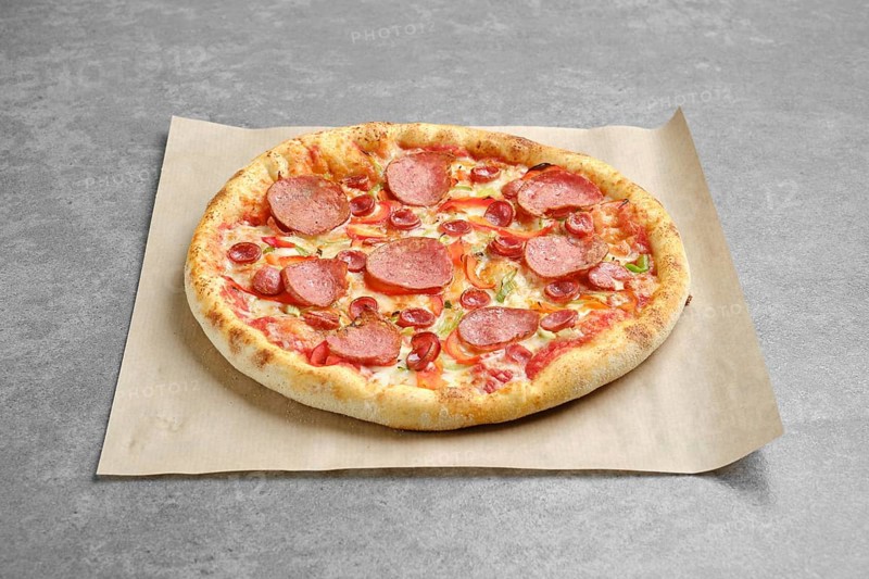Top view of pizza with sausage and colorful bell pepper on parchment