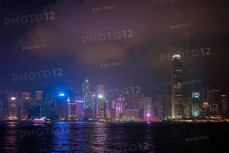 HONG KONG, CHINA, APRIL 28, 2018: Hong Kong skyline cityscape downtown skyscrapers over Victoria Harbour in the evening illuminated with tourist boat ferries, Hong Kong, China, Asia