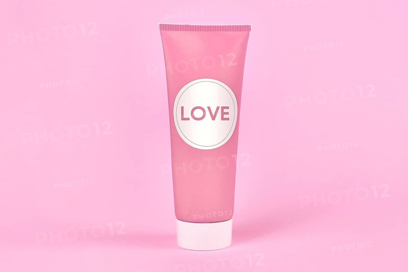 Love concept with cream tube with made up label saying LOVE on pink background