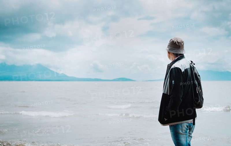 Rear view of tourist looking at a lake with volcanoes. Explorer person looking at a lake on a sunny day. Tourist man in hat from back looking at a lake with volcanoes in Rivas, Nicaragua, Central America