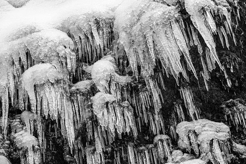 Icicles on the rock face at Skogafoss waterfall, black and white photo, Sudurland, Iceland, Europe