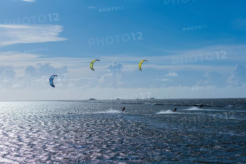Kitesurfing on the North Sea, Lüttmoorsiel, Reußenköge, on the horizon Hallig Nordstrandischmoor, Lorendamm, wind force 6, blue sky, North Frisia, Schleswig-Holstein, Germany, Europe