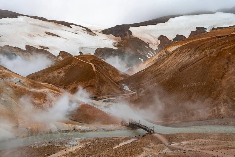 Bridge and steaming streams between colourful rhyolite mountains and snowfields, Hveradalir geothermal area, Kerlingarfjöll, Icelandic Highlands, Iceland, Europe