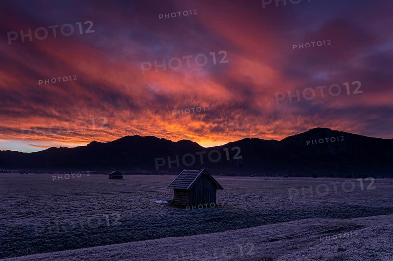 Hut in front of mountains in winter, dawn, backlight, Kochel, in the background Rabenkopf and Jochberg, foothills of the Alps, Bavaria, Germany, Europe