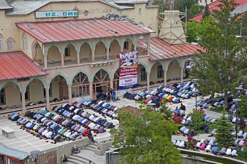 Turkish and Kurdish Muslim men in prostration praying outdoors in front of Islamic mosque for the Friday prayers in the city Van, Eastern Turkey