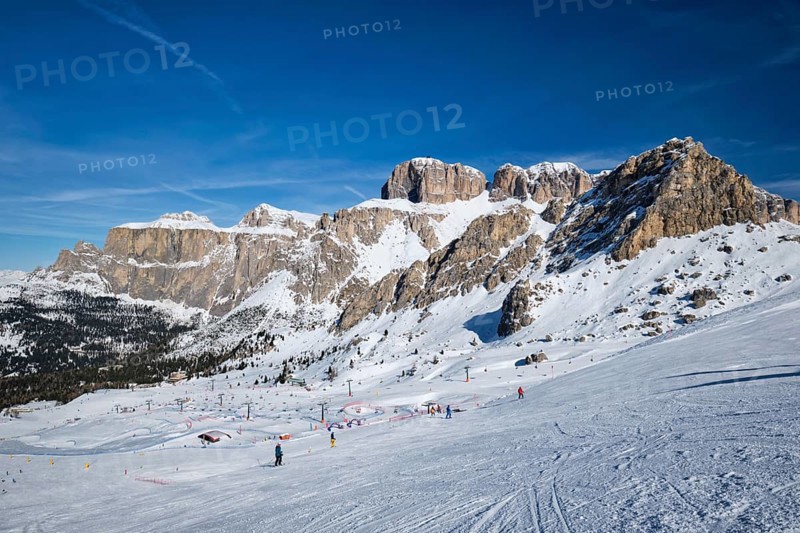 View of a ski resort piste with people skiing in Dolomites in Italy. Ski area Belvedere. Canazei, Italy, Europe
