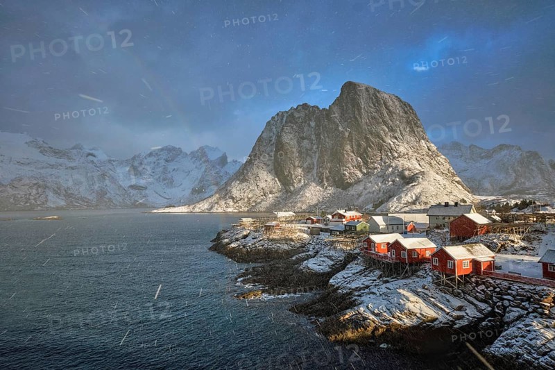 Hamnoy fishing village on Lofoten Islands, Norway with red rorbu houses. With falling snow blizzard in winter and rainbow