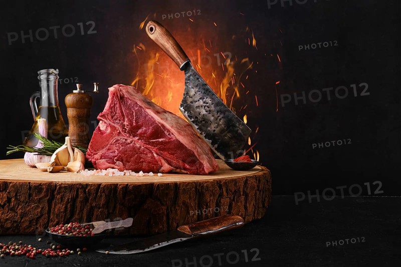 Raw porterhouse steak with ingredients for cooking on wooden log