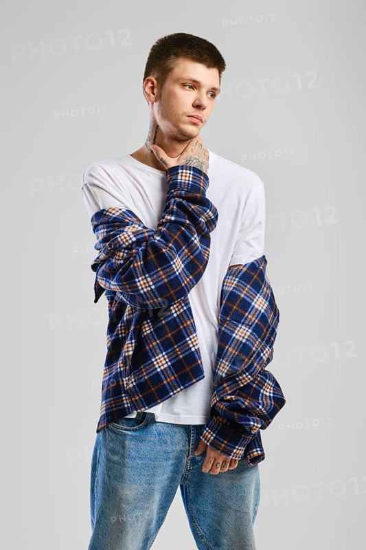 Young cocky man in checkered shirt and jeans touching his throat
