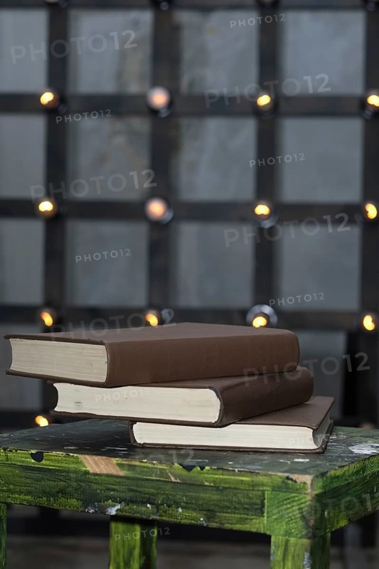 Tree big books on chair near old edison lamp mounted on wooden background