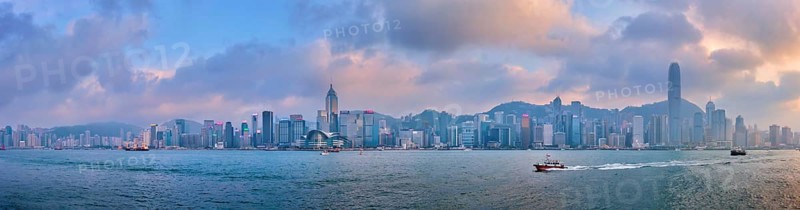 HONG KONG, CHINA, APRIL 28, 2018: Panorama of Hong Kong skyline cityscape downtown skyscrapers over Victoria Harbour in the evening on sunset with junk tourist boat ferries, Hong Kong, China, Asia