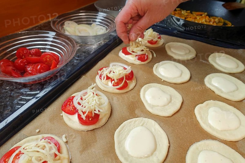 Swabian cuisine, preparation Mini-Dinnete, also Dennete, Dinnede, Dennetle, hearty, salty, raw yeast yeast dough sprinkled with grated cheese, tomatoes, vegetables, sour cream, yeast pastry, vegetarian, bake, out of the oven, typical Swabian reinterpreted, party pastry, finger food, appetisers for on the go, traditional cuisine, oven tray, man's hand, food photography, studio, Germany, Europe