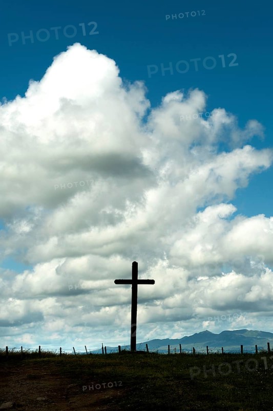 Wooden cross under a cloudy sky. Cezallier plateau. Puy de Dome departement. Auvergne-Rhone-Alpes. France