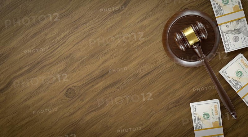 Overhead of gavel resting on a table and stacks of thousands of dollars with room for text
