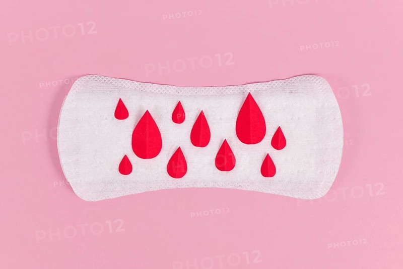 Female period concept with panty liner with symbolic paper blood drops on pink background