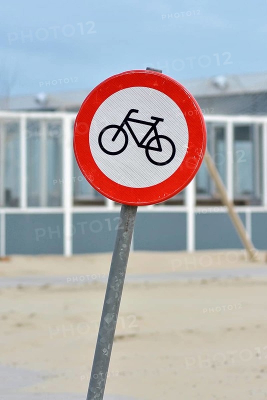 Red bicycle street warning sign on shore of Texel