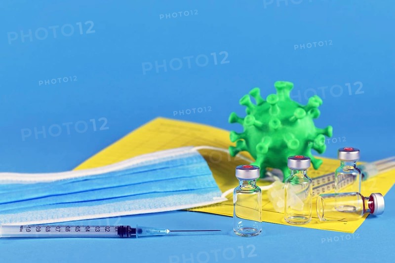 Corina virus booster vaccination concept with 4 vials and syringes, vaccination passport, virus model and face mask on blue background