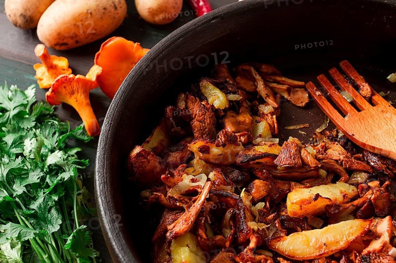 Fried chanterelles with mushrooms, in a clay pan, close-up, top view, selective focus