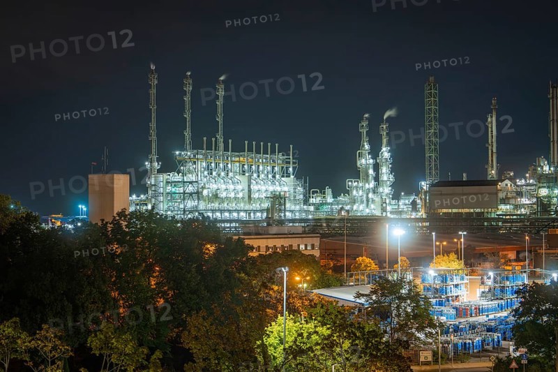 Industrial end at night with illuminated chimneys and warehouse buildings surrounded by trees and streetlights, Mannheim, Germany, Europe