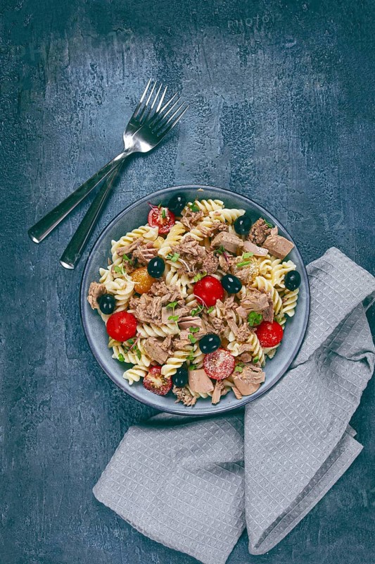 Fusilli pasta salad with canned tuna, cherry tomatoes and olives, parmesan, microgreens, homemade, no people