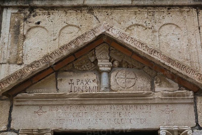 Close-up of carved letters and ancient symbols on old limestone building facade with triangular pediment at ancient 3rd century Roman ruins of Salona near Solin, Croatia, Europe