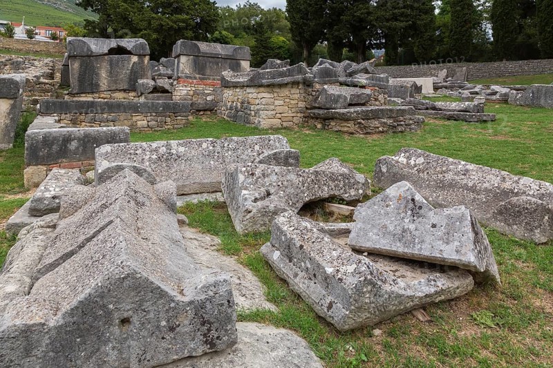 Close-up of old large and heavy broken pieces of cut and carved grey granite, stone and wall structures in cemetery at ancient 3rd century Roman ruins of Salona near Solin in late summer, Croatia, Europe