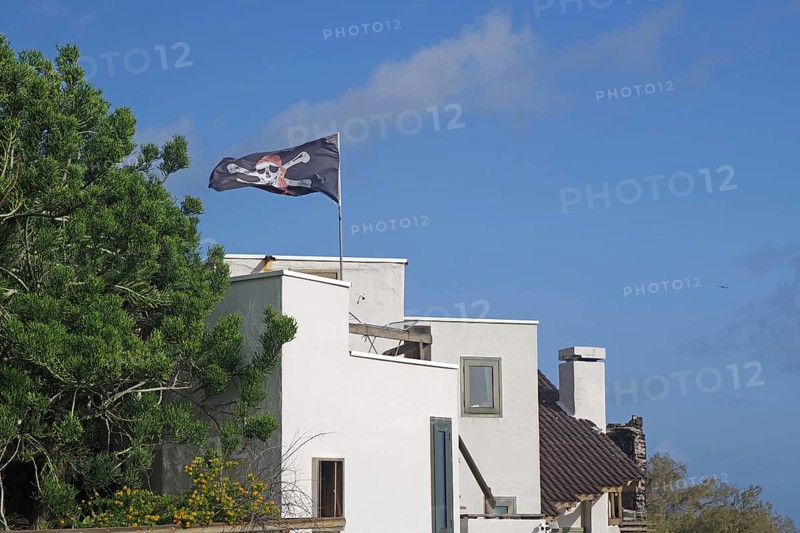 A white house with a waving pirate flag under a blue sky, San Andres, La Palma, Canary Islands, Spain, Europe