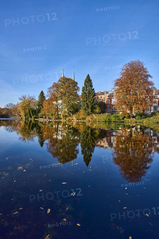 Mill pond with trees, general buildings against a cloudless blue sky, symmetrical reflections on the water surface, Hanseatic city of Lübeck, Schleswig-Holstein, Germany, Europe