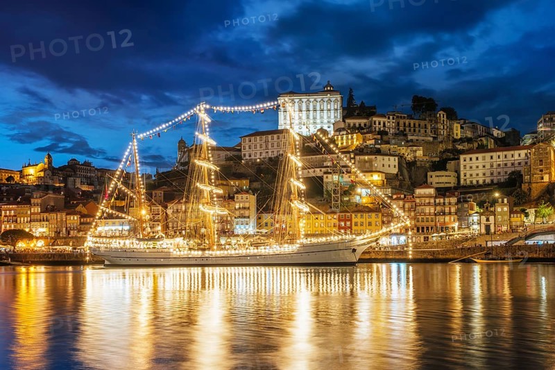View of Porto city and Douro river with sailing ship from famous tourist viewpoint Marginal de Gaia riverfront in the evening. Porto, Vila Nova de Gaia, Portugal, Europe