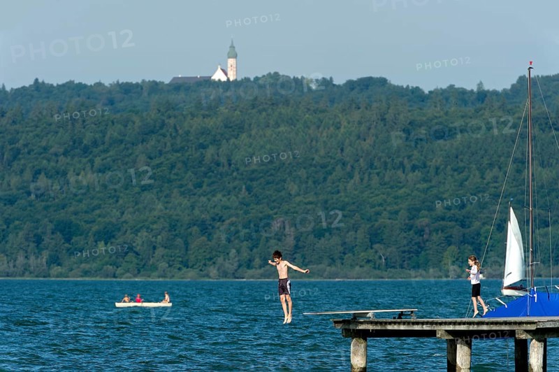 Boy and girl bathing in the lake, children jumping over diving board into the water, jetty of Dießen am Lake Ammer, behind Andechs monastery, Upper Bavaria, Bavaria, Germany, Europe