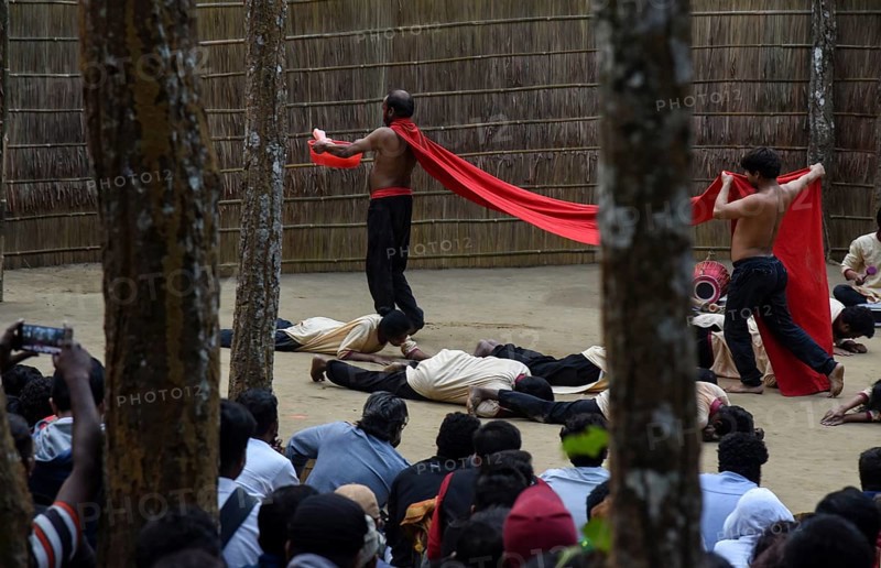 People enjoying a drama during 'Under The Sal Tree' Theatre Festival on December 15, 2021 in Goalpara, Assam, India. Under the Sal Tree theatre festival is one of its kind, held at Badungduppa Kala Kendra in the middle of a dense Sal forest in rural Lower Assam. The festival was started by Sukracharjya Rabha, a widely respected theatre personality of Assam, in 2008. He wanted to spread a message of coexistence with nature and made in a completely natural setting inside a jungle, which made the theatre festival unique