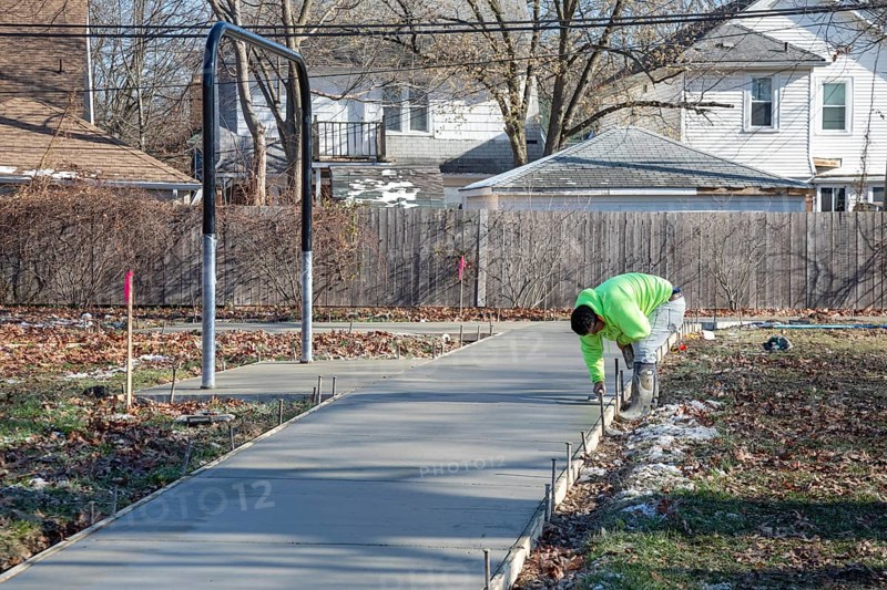 Detroit, Michigan - Workers pour and finish concrete for walking paths in Three Mile Park in Detroit's Morningside neighborhood.