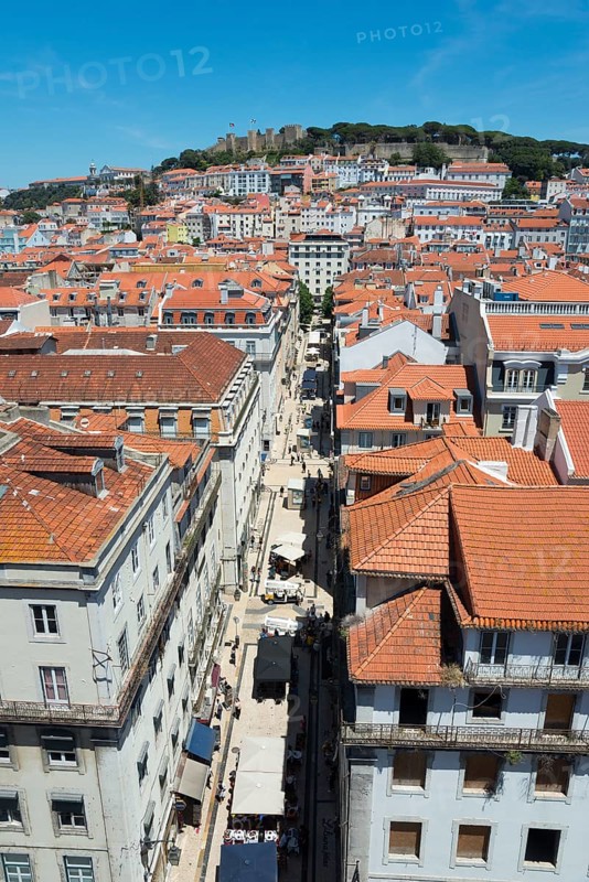 Aerial view of a narrow alley with tall buildings and red tiled roofs in a sunny city, view of castle, viewpoint, Miraduoro Terracos Do Carmo, view of Castelo de São Jorge, Saint George Castle, Old Town, Lisbon, Lisboa, Portugal, Europe