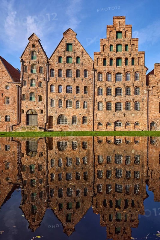 Historic salt warehouses, brick buildings reflected on the water surface of the Trave, blue sky with veil clouds, Hanseatic city of Lübeck, independent city, Schleswig-Holstein, Germany, Europe