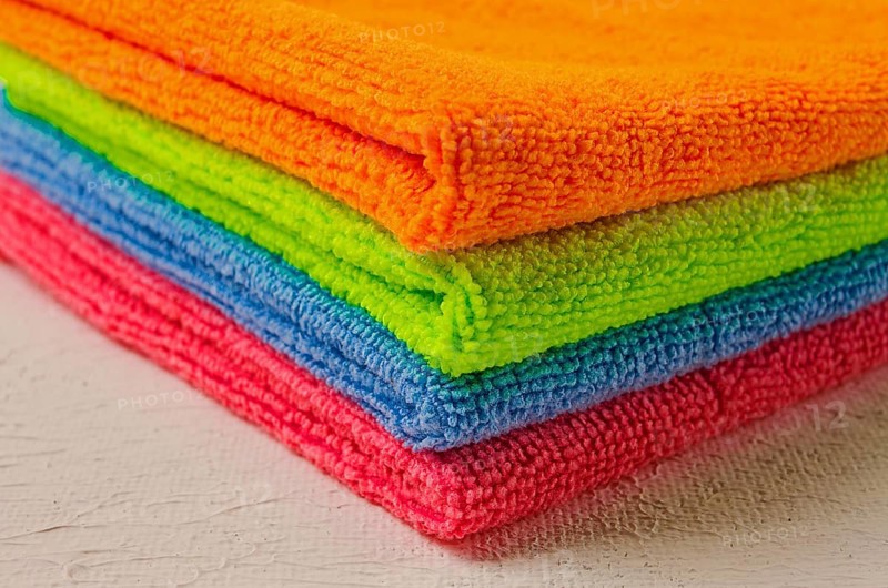 A stack of colored cloth, microfiber, for cleaning the house, on a white table, horizontal, no people