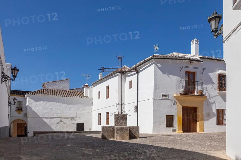 A sunny alleyway with white traditional buildings and cobbled streets under a clear blue sky, Ronda, Andalusia, Spain, Europe