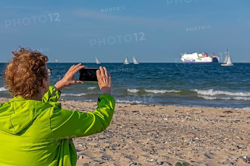 Older woman taking photos of boats, sailing boats, ferry, smartphone, Kieler Woche, Falckensteiner Strand, Kiel Fjord, Kiel, Schleswig-Holstein, Germany, Europe